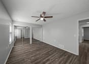 Thumbnail 9 of 17 - A room with a ceiling fan and wooden flooring.
