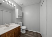Thumbnail 10 of 17 - A bathroom with a toilet, sink, and mirror.