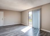 Thumbnail 8 of 16 - an empty living room with a sliding glass door to a balcony