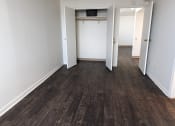 Thumbnail 9 of 21 - an empty living room with wooden floors and white walls