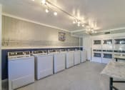 Thumbnail 14 of 15 - A laundromat with a row of washers and dryers.