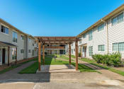 Thumbnail 13 of 14 - a pathway between two apartment buildings with a wooden canopy