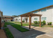 Thumbnail 14 of 14 - a pathway between two apartment buildings with a wooden pergola