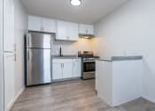 Thumbnail 1 of 6 - an empty kitchen with white cabinets and a stainless steel refrigerator