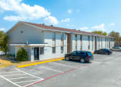 Thumbnail 6 of 6 - a white building with cars parked in a parking lot
