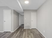 Thumbnail 8 of 25 - the spacious living room and hallway of a manufactured home with white walls and wood floors