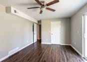 Thumbnail 21 of 27 - A room with a ceiling fan and wooden floors.
