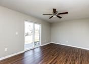 Thumbnail 6 of 27 - A room with a ceiling fan and sliding glass doors.