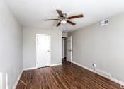 Thumbnail 23 of 27 - A room with a ceiling fan and wooden floors.