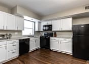 Thumbnail 14 of 27 - A kitchen with black appliances and white cabinets.