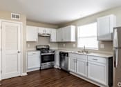 Thumbnail 10 of 27 - A kitchen with white cabinets and appliances.