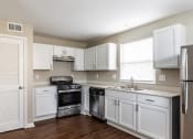 Thumbnail 13 of 27 - an empty kitchen with white cabinets and stainless steel appliances
