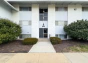 Thumbnail 14 of 15 - the front entrance to a white building with bushes and a sidewalk