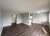 Thumbnail 2 of 15 - a living room and kitchen with wood flooring and white walls