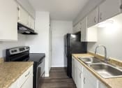 Thumbnail 5 of 15 - a kitchen with white cabinets and black appliances and granite counter tops