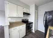 Thumbnail 6 of 15 - a kitchen with white cabinets and a black stove and refrigerator
