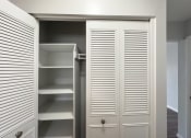 Thumbnail 8 of 15 - a walk in closet with white closet doors and shelving