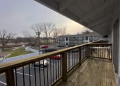 Thumbnail 9 of 15 - a balcony with a wooden railing overlooking a parking lot