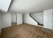 Thumbnail 2 of 12 - a living room with a carpeted floor and a staircase in the background