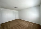 Thumbnail 7 of 12 - a bedroom with white walls and a brown carpet