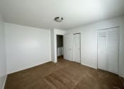 Thumbnail 6 of 12 - a bedroom with white walls and a brown carpet