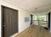 Thumbnail 10 of 12 - a front porch with a wooden floor and a door with a handle