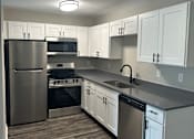 Thumbnail 8 of 17 - A modern kitchen with a stainless steel refrigerator and a wall-mounted oven.