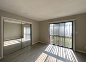 Thumbnail 5 of 8 - an empty bedroom with a sliding glass door and a mirrored closet