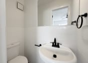 Thumbnail 7 of 15 - A white bathroom with a toilet, sink and mirror.