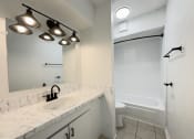 Thumbnail 8 of 15 - A white bathroom with a sink, mirror, and bathtub.
