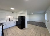 Thumbnail 2 of 15 - A black refrigerator in a kitchen with white cabinets and a marble backsplash.