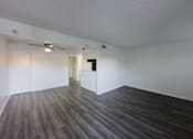 Thumbnail 2 of 19 - A room with a ceiling fan and wooden flooring.