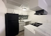 Thumbnail 3 of 19 - A kitchen with a black fridge and white countertops.