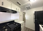 Thumbnail 4 of 19 - A kitchen with black appliances and white cabinets.