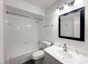 Thumbnail 10 of 19 - A white bathroom with a toilet, sink, and shower.