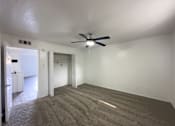 Thumbnail 5 of 19 - A room with a ceiling fan and carpeted floor.