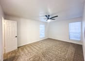 Thumbnail 6 of 19 - A room with a ceiling fan and carpeted floor.