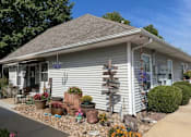 Thumbnail 15 of 17 - A house with a grey roof and a white wall with a garden in front.