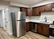Thumbnail 20 of 40 - A kitchen with a stainless steel refrigerator and wooden cabinets.