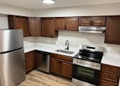 Thumbnail 21 of 40 - A kitchen with wooden cabinets and a stainless steel refrigerator.