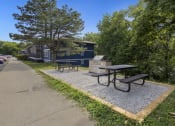 Thumbnail 11 of 14 - a picnic area with benches and a picnic table next to a sidewalk