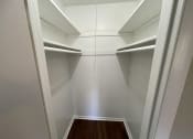 Thumbnail 5 of 7 - a walk in closet with white shelves and a wood floor
