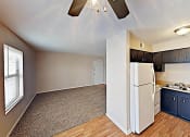 Thumbnail 10 of 15 - an empty living room with a kitchen with a refrigerator