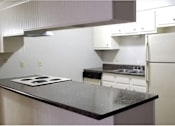 Thumbnail 15 of 15 - A kitchen with a black counter top and white appliances.