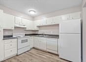 Thumbnail 9 of 15 - A kitchen with white appliances and cabinets.