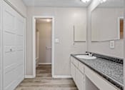 Thumbnail 6 of 15 - A bathroom with a sink, mirror, and white cabinets.