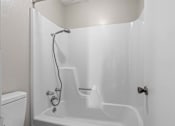 Thumbnail 11 of 15 - A white bathroom with a tub, toilet, and shower.