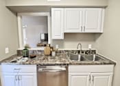 Thumbnail 19 of 25 - A kitchen with a granite countertop and white cabinets.