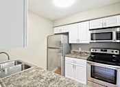 Thumbnail 14 of 25 - A kitchen with a granite countertop and stainless steel appliances.