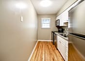Thumbnail 11 of 25 - A kitchen with wooden floors and white cabinets.